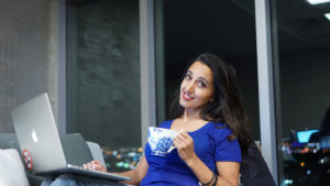 Paula in navy blue top holding a cup with a laptop