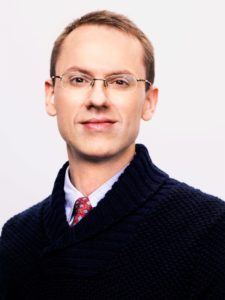 Photo of Dr. Wade Pfau in a black sweater with a button down shirt and tie