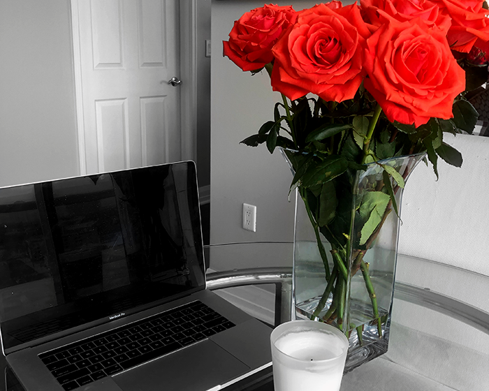 Laptop, a candle and roses on a table
