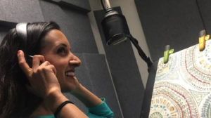 Image of Paula in front of a microphone with headphones on