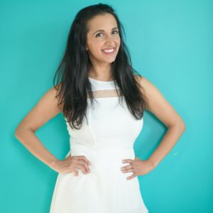 Photo of Paula Pant in white dress on teal background