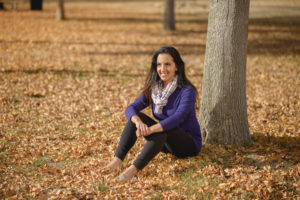 Photo of Paula Pant sitting on autumn ground surrounded by leaves