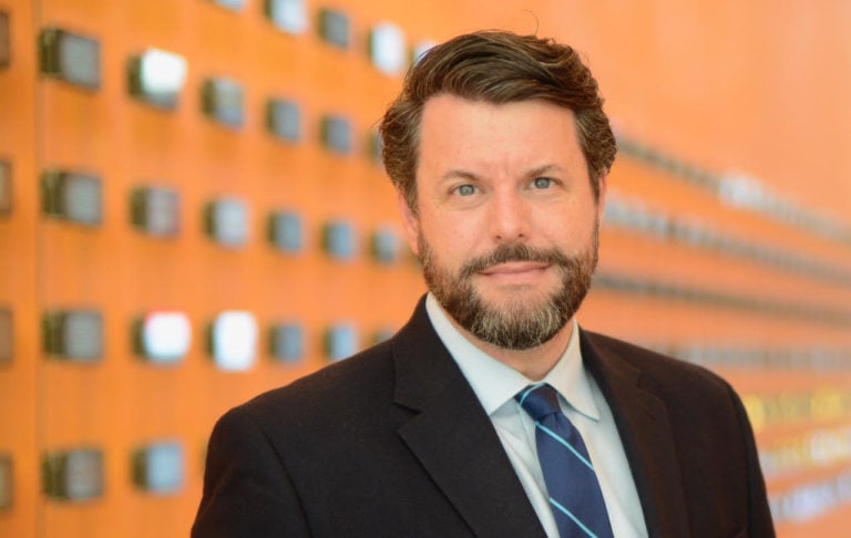 Photo of Charles Duhigg in a suit against an orange background