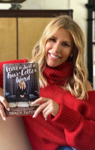 Tracy Tutor in red sweater holding her book Fear is Just a Four Letter Word