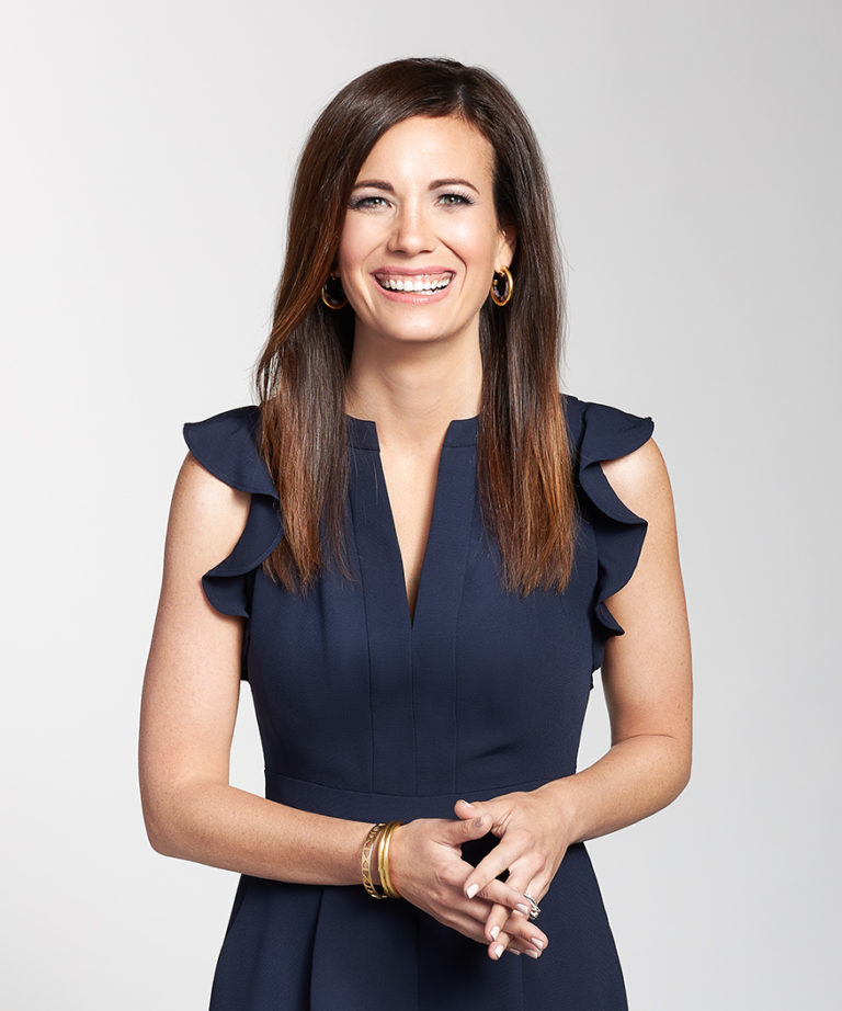 Rachel Cruze in a navy blue dress against grey background