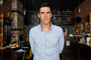 Ryan Holiday in a blue shirt in a bookstore
