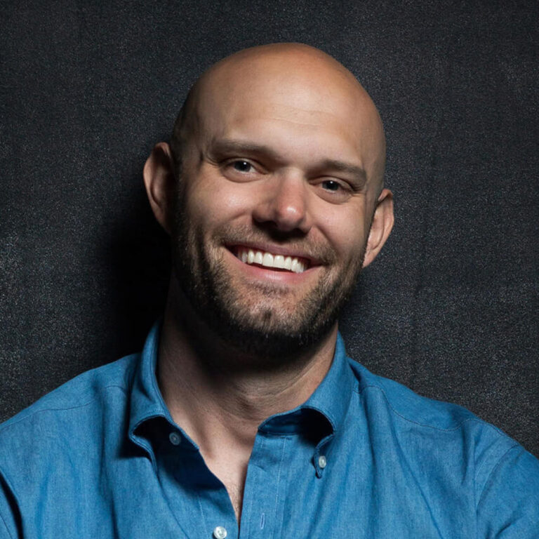 James Clear smiling in a photoshoot to promote Atomic Habits - where he discusses creating habits.