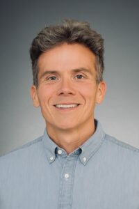 Dr. Daniel Crosby, an expert in Financial Success, smiling in front of the camera for a formal shoot.