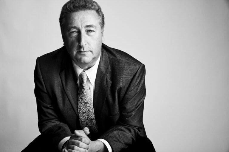 Barry Ritholtz, the author of "How NOT to Invest" wearing a suit and posing in front of the camera